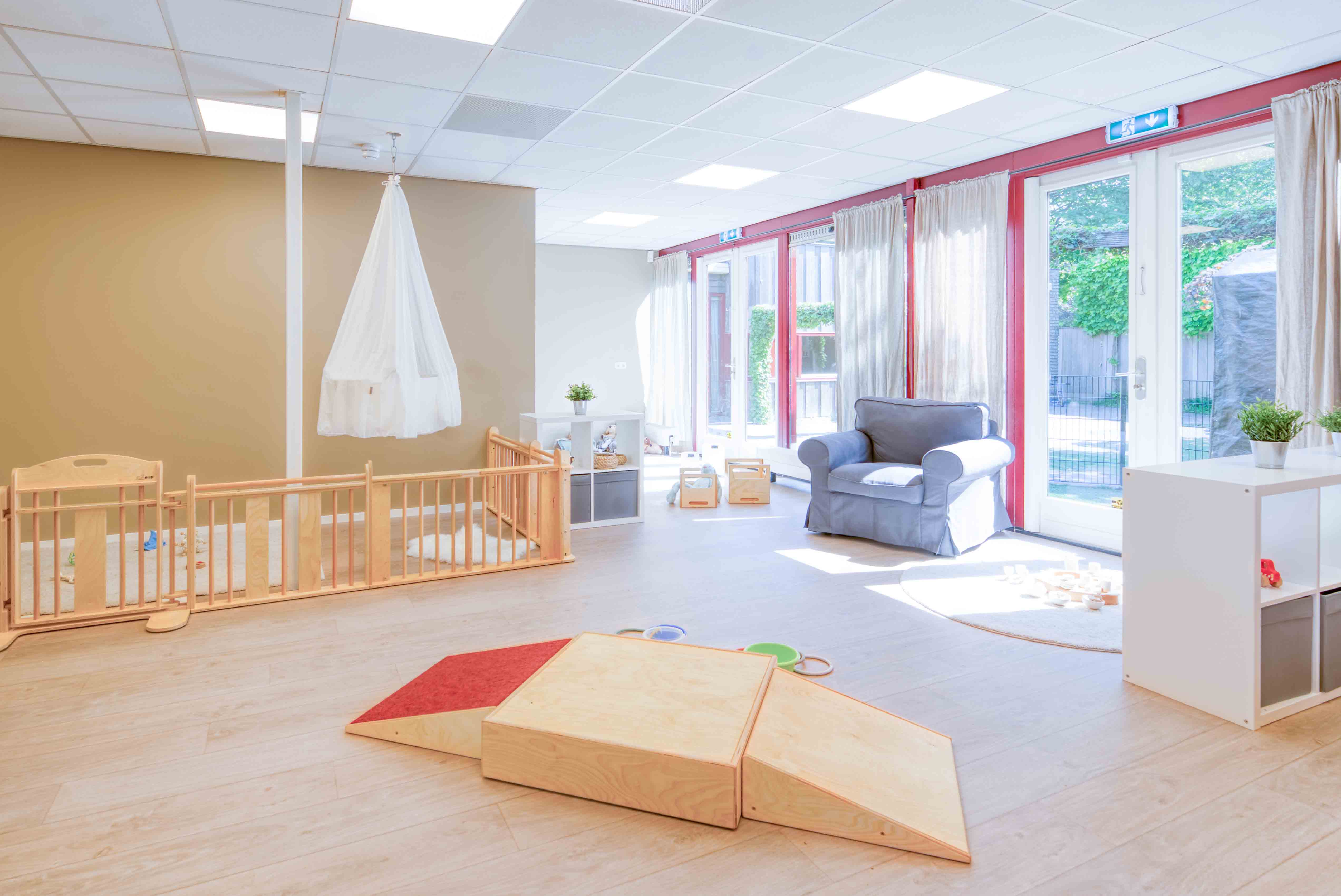 Inrichting babygroep met houten spelmaterialen en een grondbox