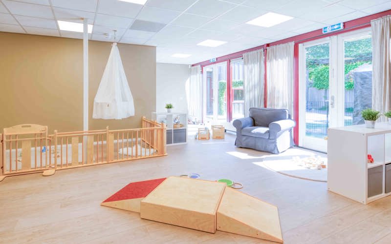 Inrichting babygroep met houten spelmaterialen en een grondbox