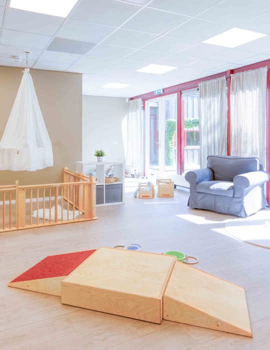 Inrichting babygroep met houten spelmaterialen en een grondbox