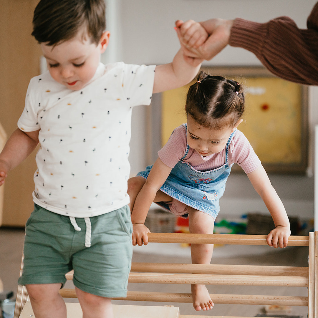 Jongen en meisje lopen over Pikler klimdriehoek