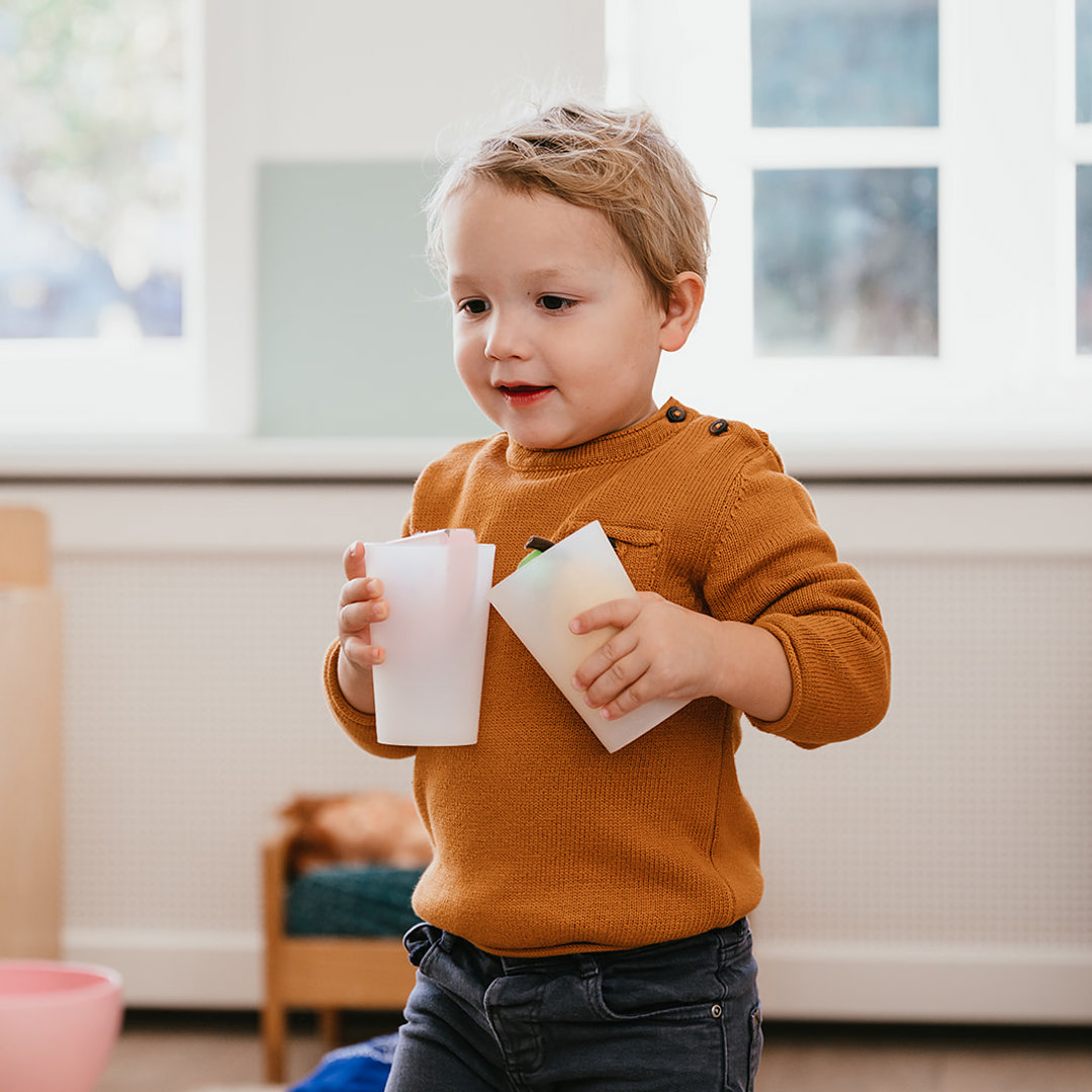 Peuter loopt met drinkbekers in hand