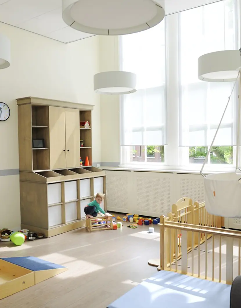 kind speelt met houten speelgoed op de babygroep