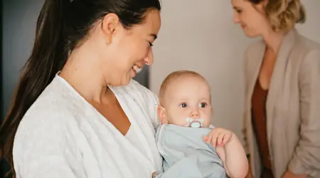 Lachende Pedagogisch Medewerker houdt baby vast
