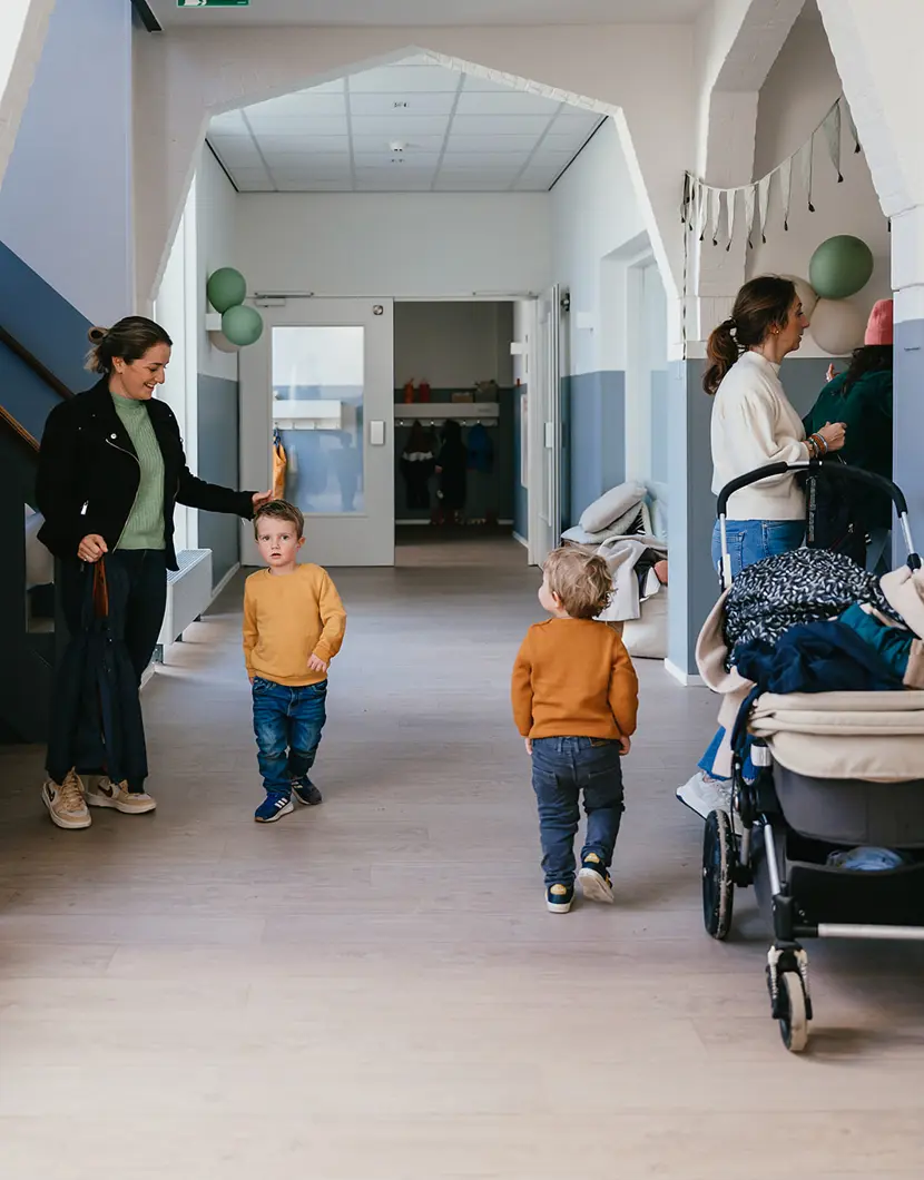 Kinderen en moeders lopen in gang van kinderopvang