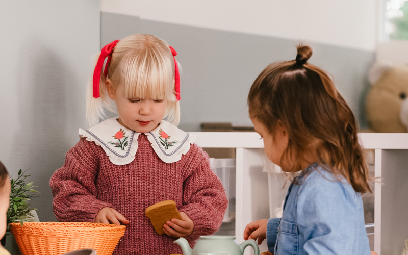 2 jonge kinderen spelen aan een klein tafeltje met stoelen