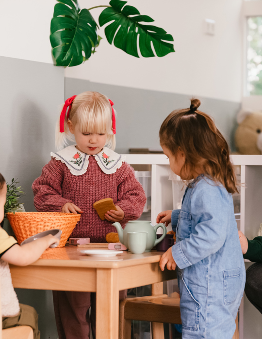 2 jonge kinderen spelen aan een klein tafeltje met stoelen
