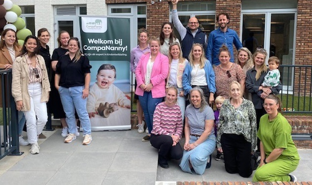 groep mensen poseren bij bord lachen naar camera