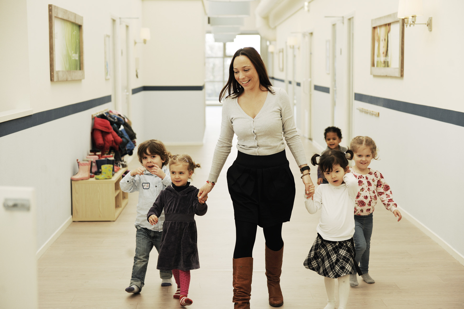 pedagogisch medewerker loopt met kinderen door gang kinderopvang