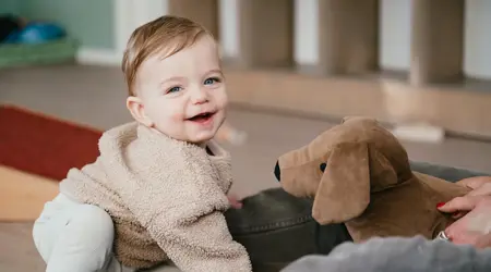 Kind met knuffelhond lacht in camera