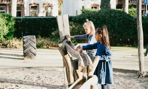 Twee meisjes spelen in zandbak van kinderopvang