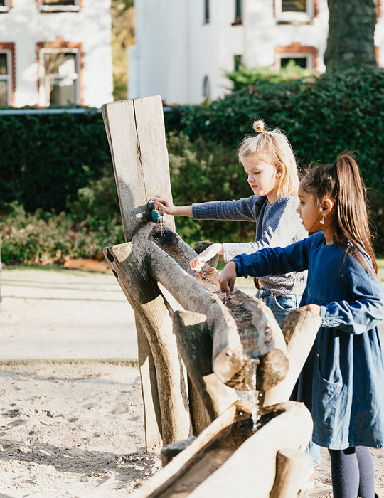 Twee meisjes spelen in zandbak van kinderopvang