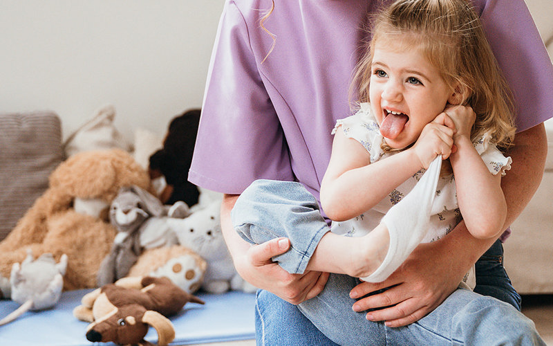 Peuter trekt sok uit op schoot van vrouw