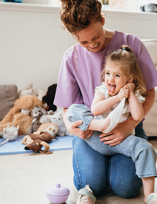 Peuter trekt sok uit op schoot van vrouw