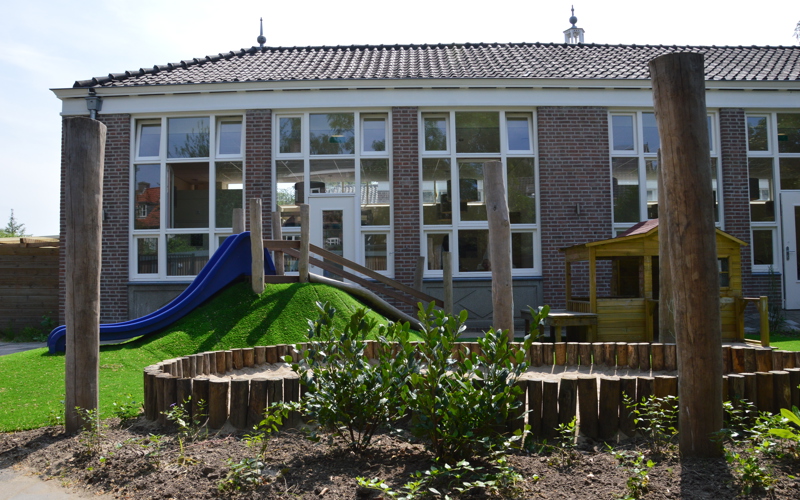 speeltuin kinderopvang met glijbaan en houten huisje