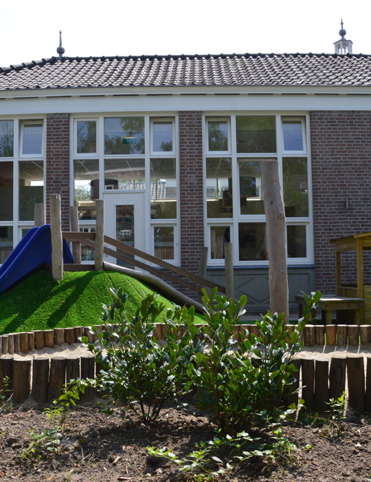 speeltuin kinderopvang met glijbaan en houten huisje