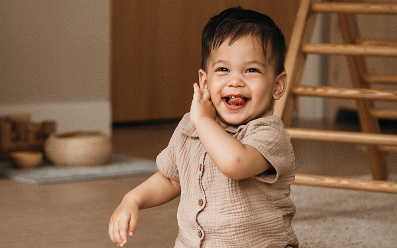 Dreumes zit op de grond en lacht naar camera