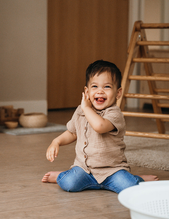 Dreumes zit op de grond en lacht naar camera