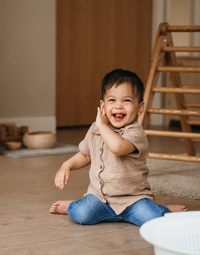 Dreumes zit op de grond en lacht naar camera