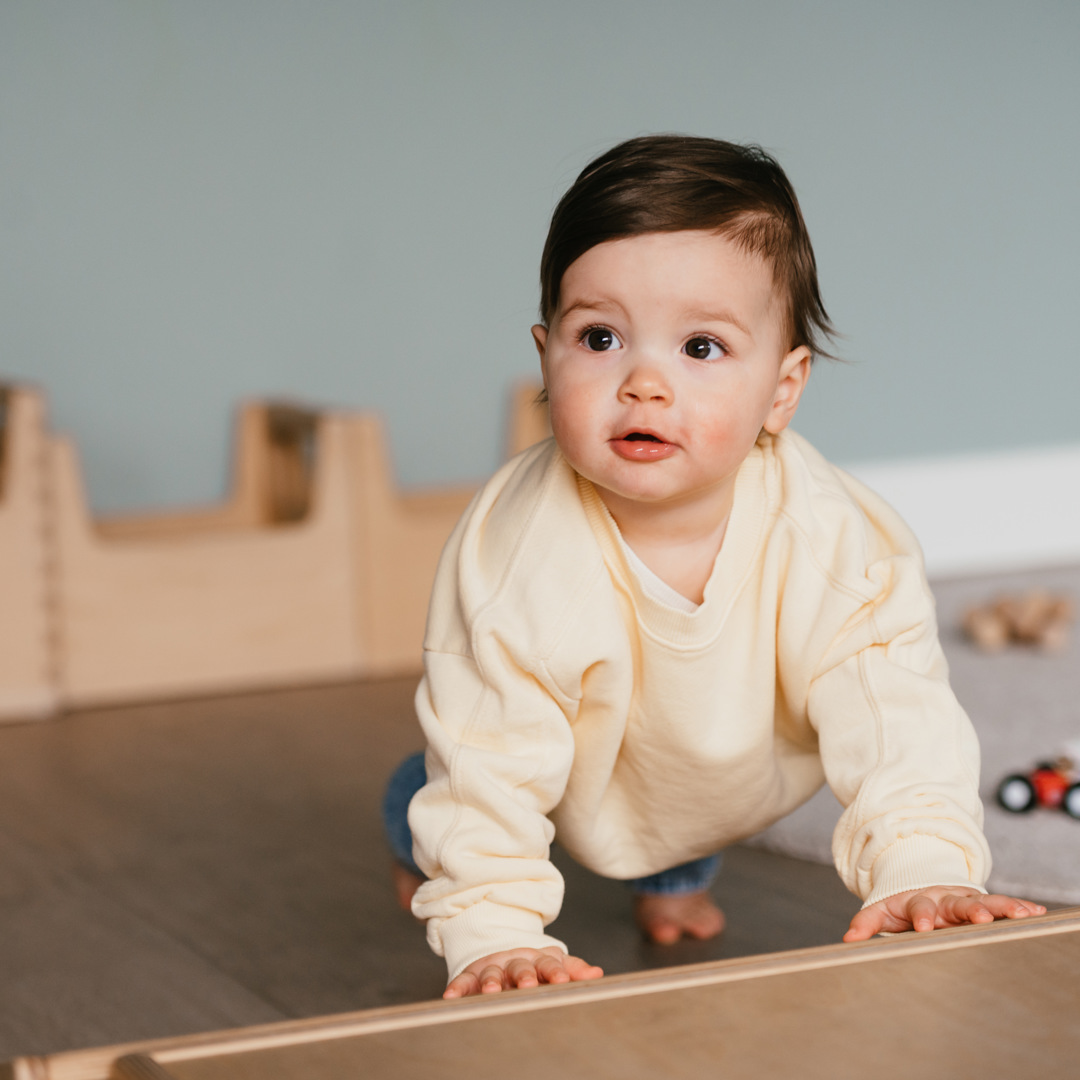 Baby klimt op kruipkist op kinderopvang