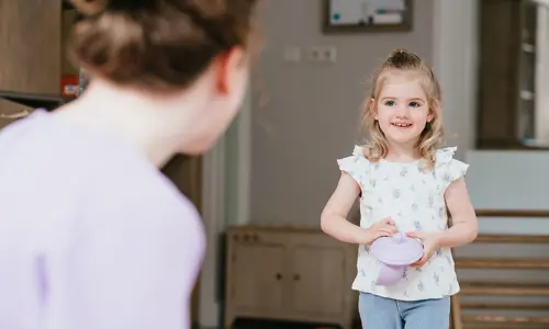 Meisje lacht naar vrouw op kinderopvang
