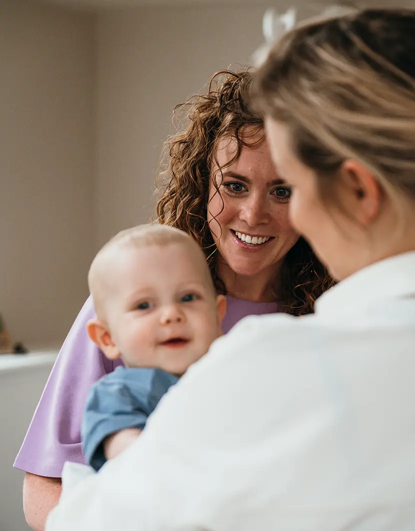 Ouder geeft baby aan pedagogisch medewerker op kinderopvang