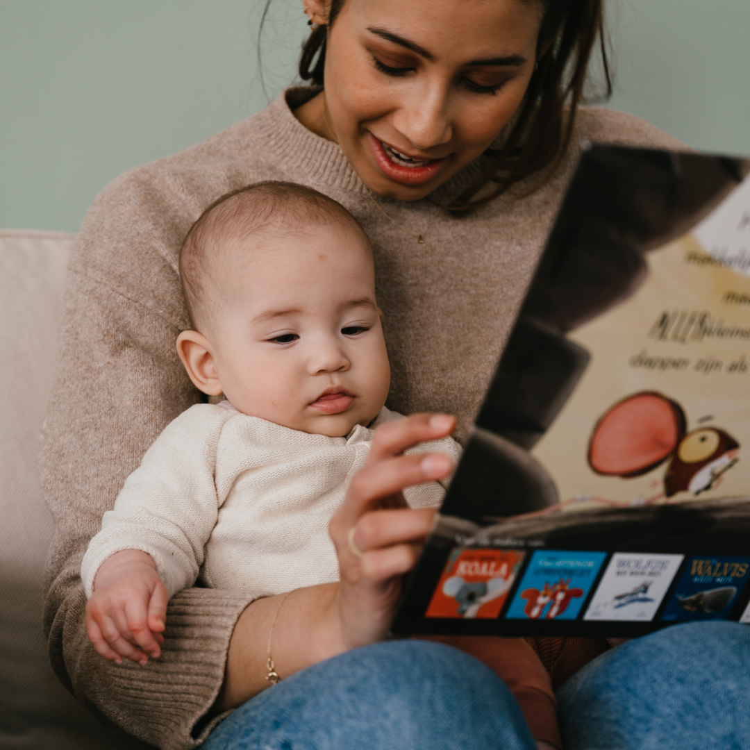 Pedagogisch Medewerker kinderopvang leest boekje voor aan baby