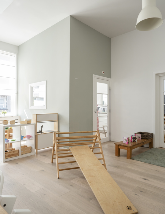 groep kinderopvang met klimdriehoek en houten spelmaterialen