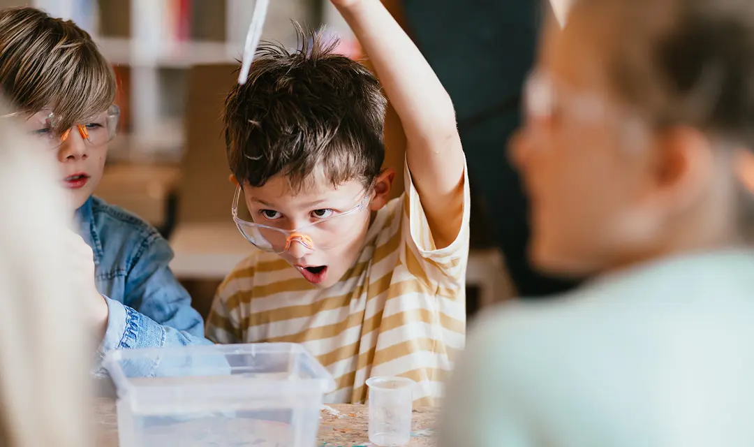 Jongen met veiligheidsbril doet een experiment op de BSO
