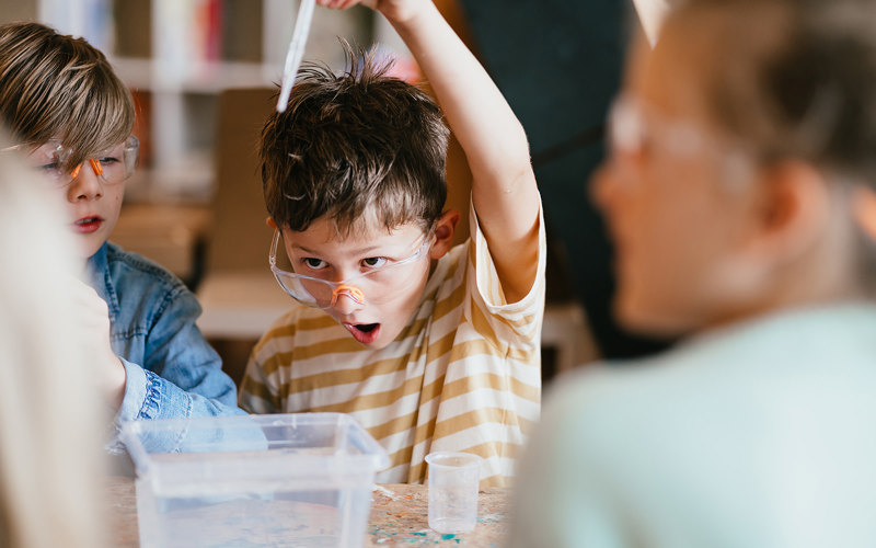 Jongen met veiligheidsbril doet een experiment op de BSO