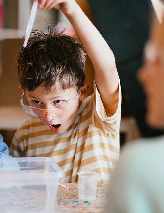 Jongen met veiligheidsbril doet een experiment op de BSO
