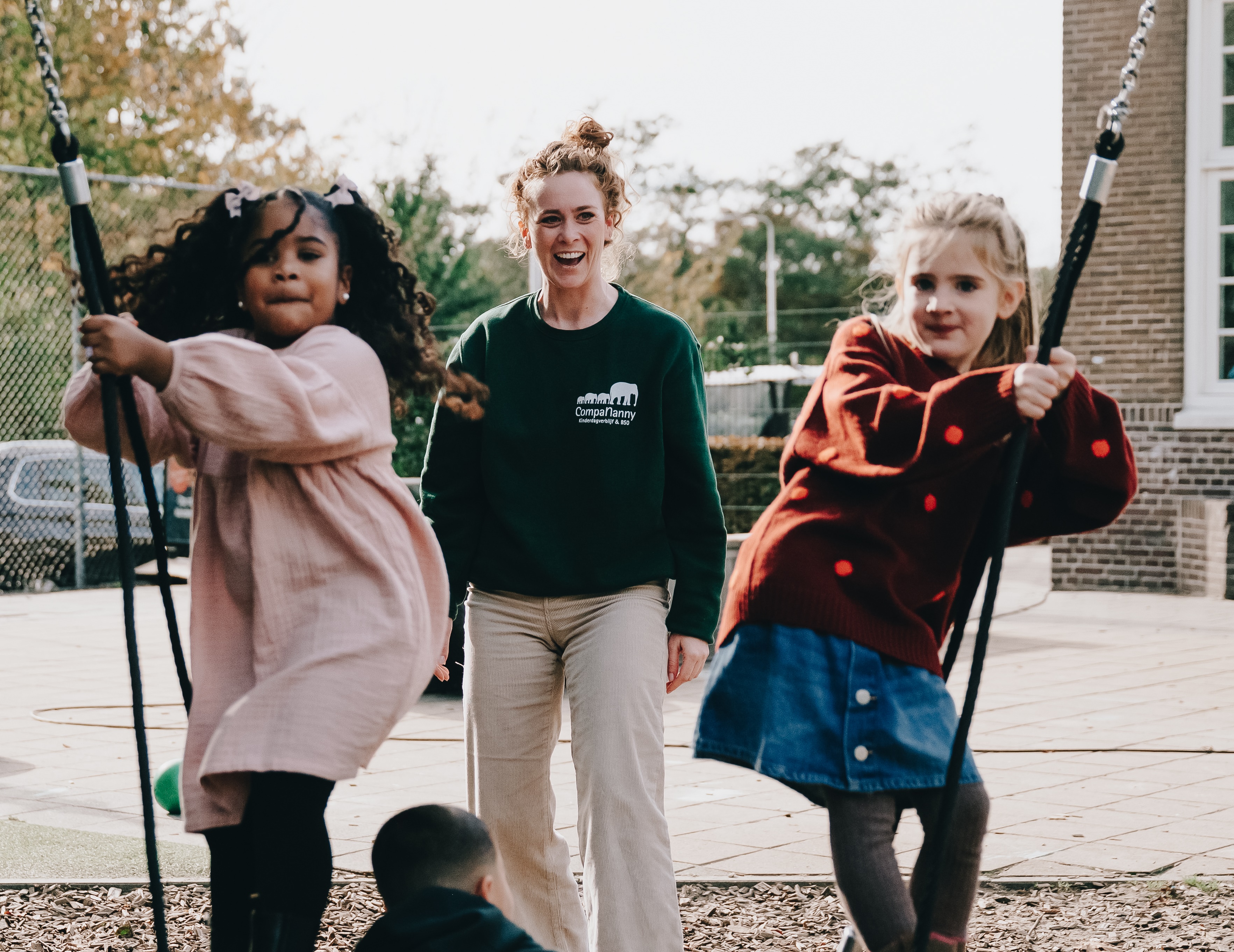 twee kinderen schommel en vrouw lacht naar de kinderen