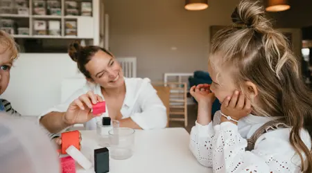 Pedagogisch Medewerker speelt en lacht met kinderen aan tafel