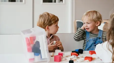 Twee peuters zitten aan tafel en spelen met passief speelgoed