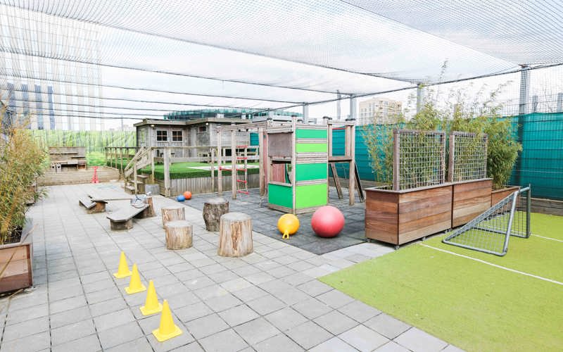 buiten speelruimte van kinderopvang met speeltoestel en voetbalveld