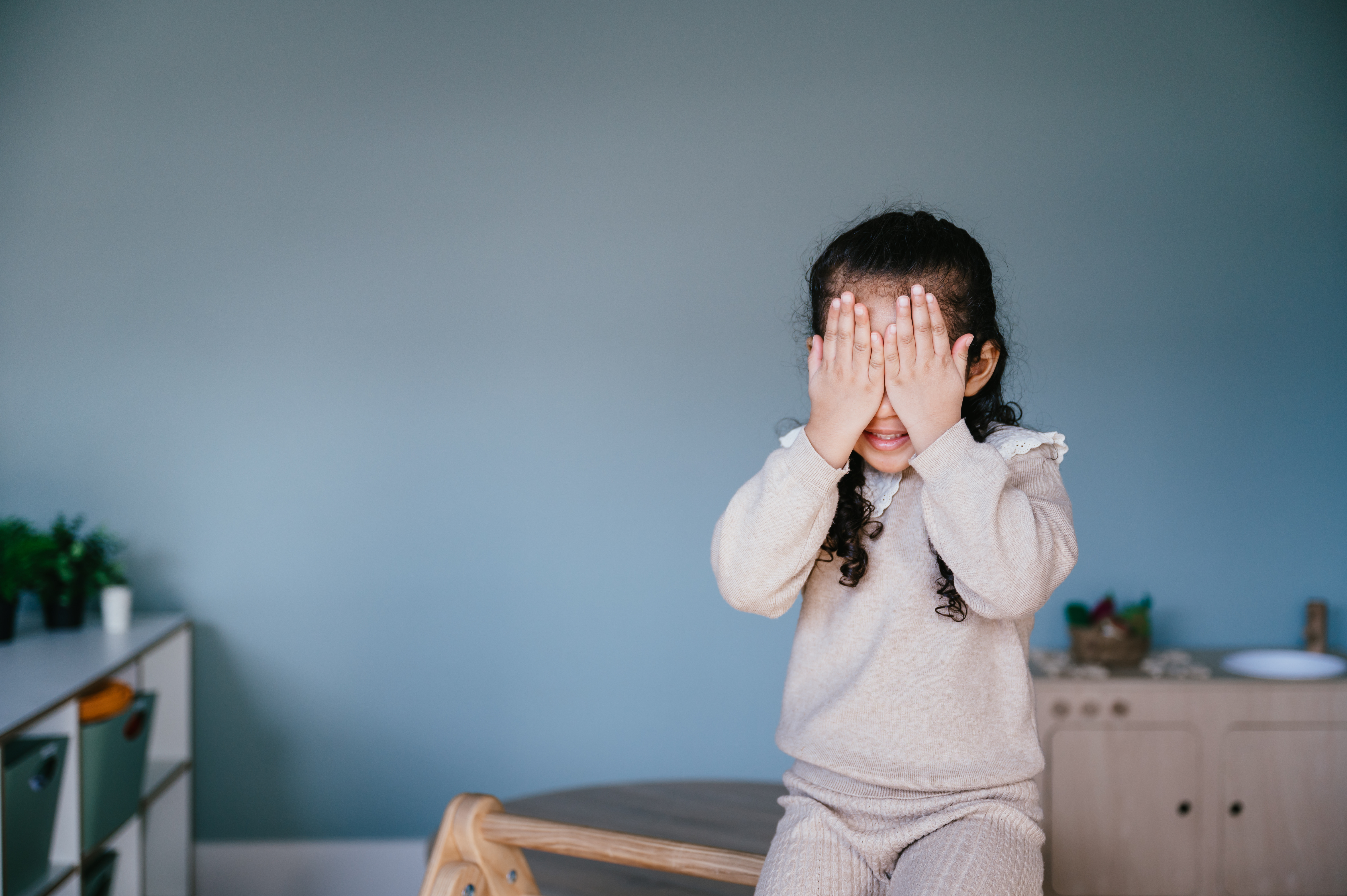 Meisje lacht en zit met handen voor haar ogen