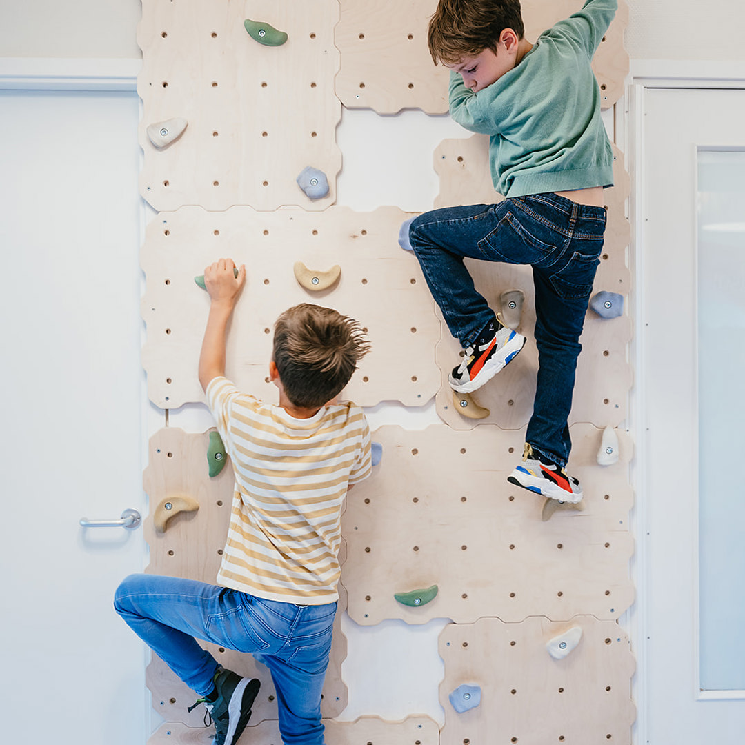 Twee jongen klimmen op een klimmuur