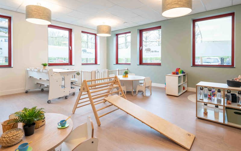 babygroep inrichting met houten meubels grondbox en klimdriehoek