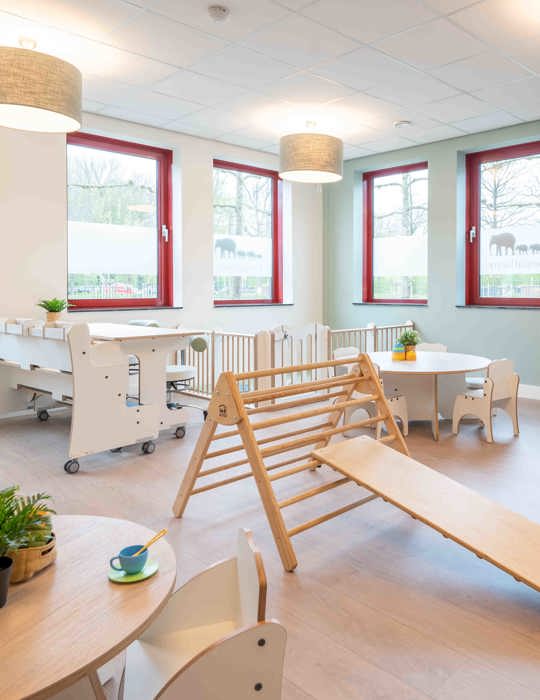 babygroep inrichting met houten meubels grondbox en klimdriehoek