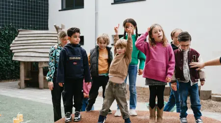 Groep kinderen staat in tuin van kinderopvang