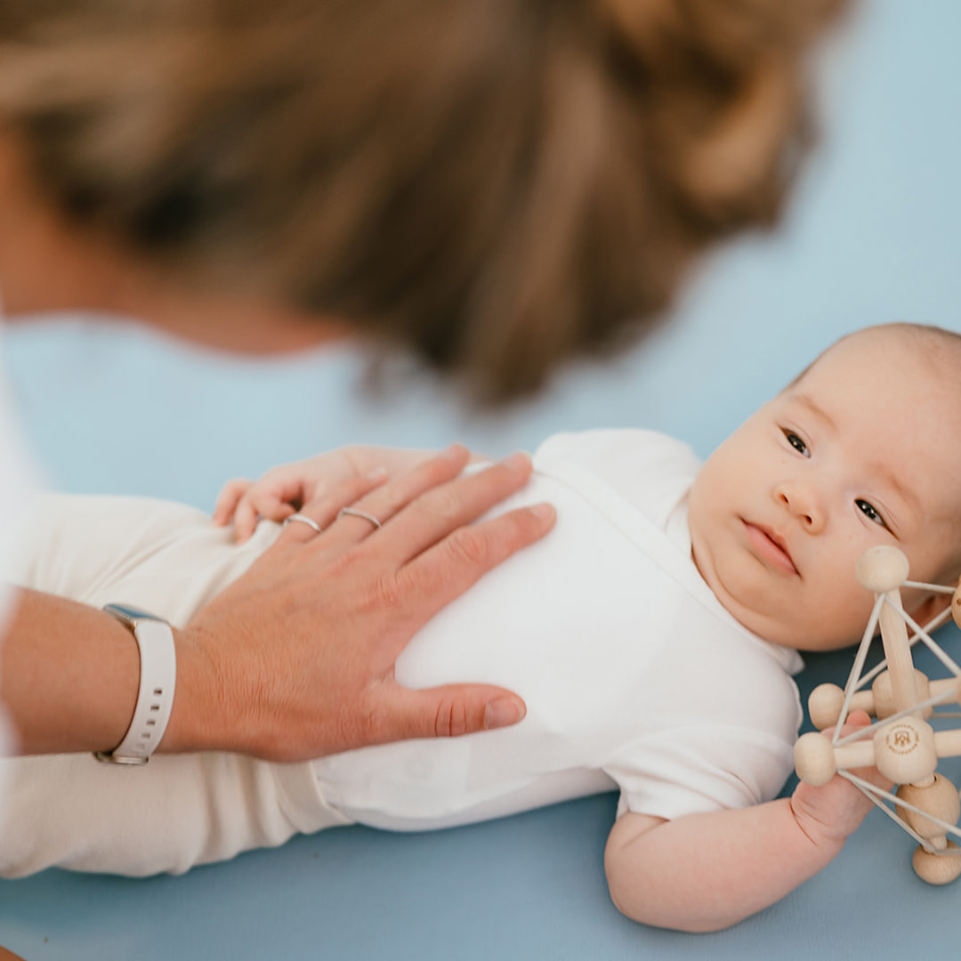 Vrouw houdt baby met houten speelgoed vast