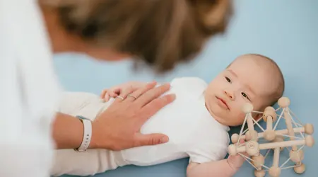 Vrouw houdt baby met houten speelgoed vast