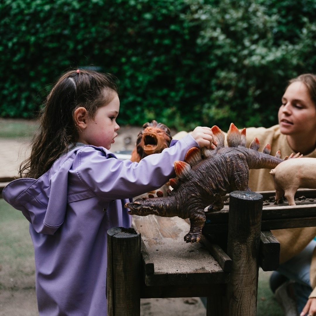 meisje speelt in tuin met speelgoed met pedagogisch medewerker