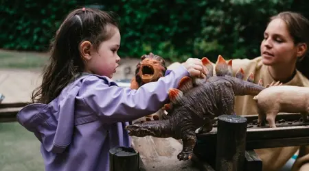 meisje speelt in tuin met speelgoed met pedagogisch medewerker