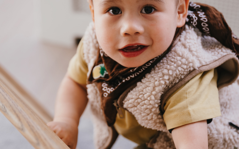 Kind klimt op een klimdriehoek en kijkt in camera