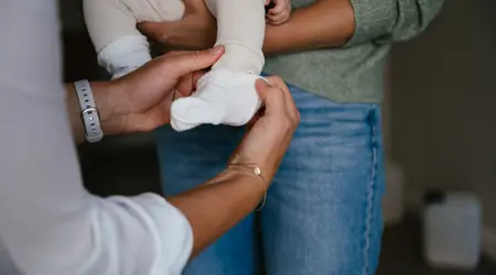Vrouw doet sok aan bij baby