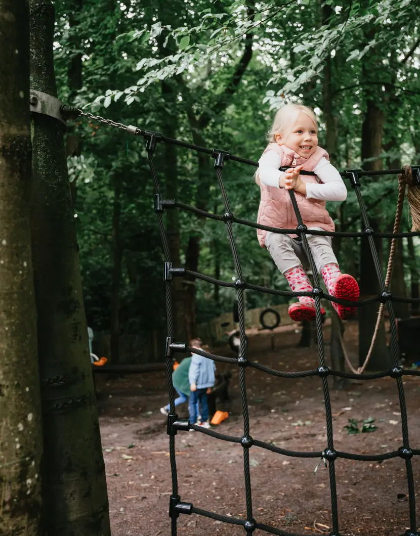 Meisje speelt op klimrek in tuin en lacht