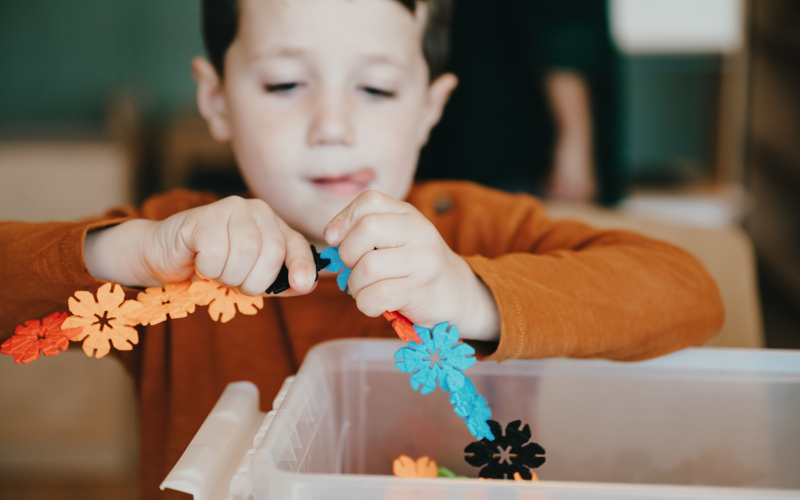 Kind heeft speelgoed in handen en bouwt