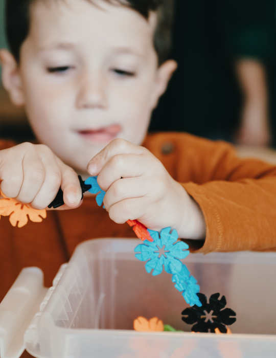 Kind heeft speelgoed in handen en bouwt