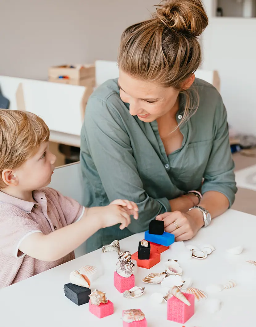 Vrouw en kind spelen aan tafel met speelgoed