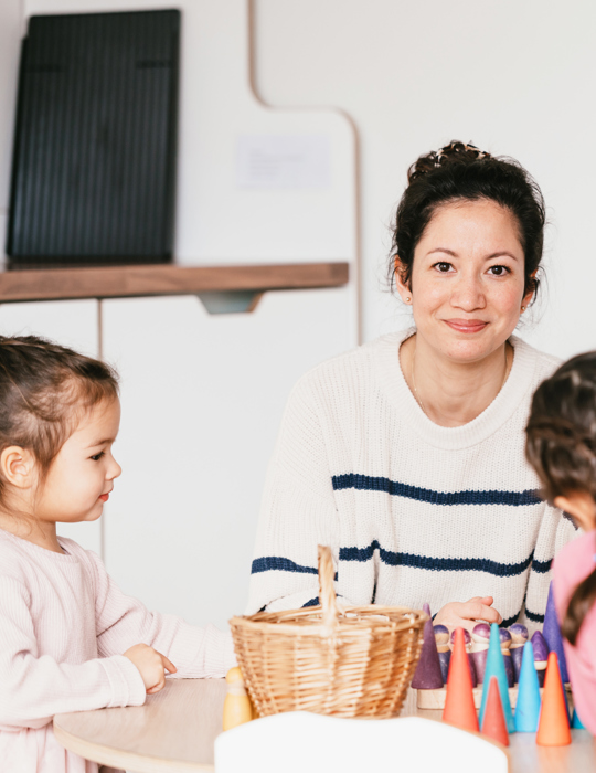 Vrouw zit aan tafel met kinderen en kijkt in de camera